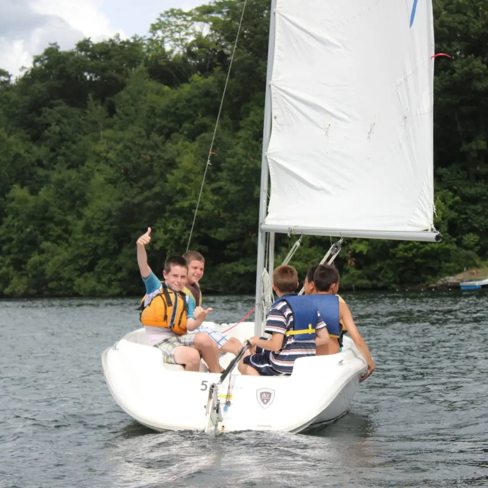 Thumbs up from kids on a sailboat during Regatta Point summer camp