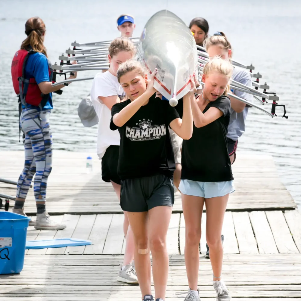 Kids carrying a rowing boat during learn to row camp